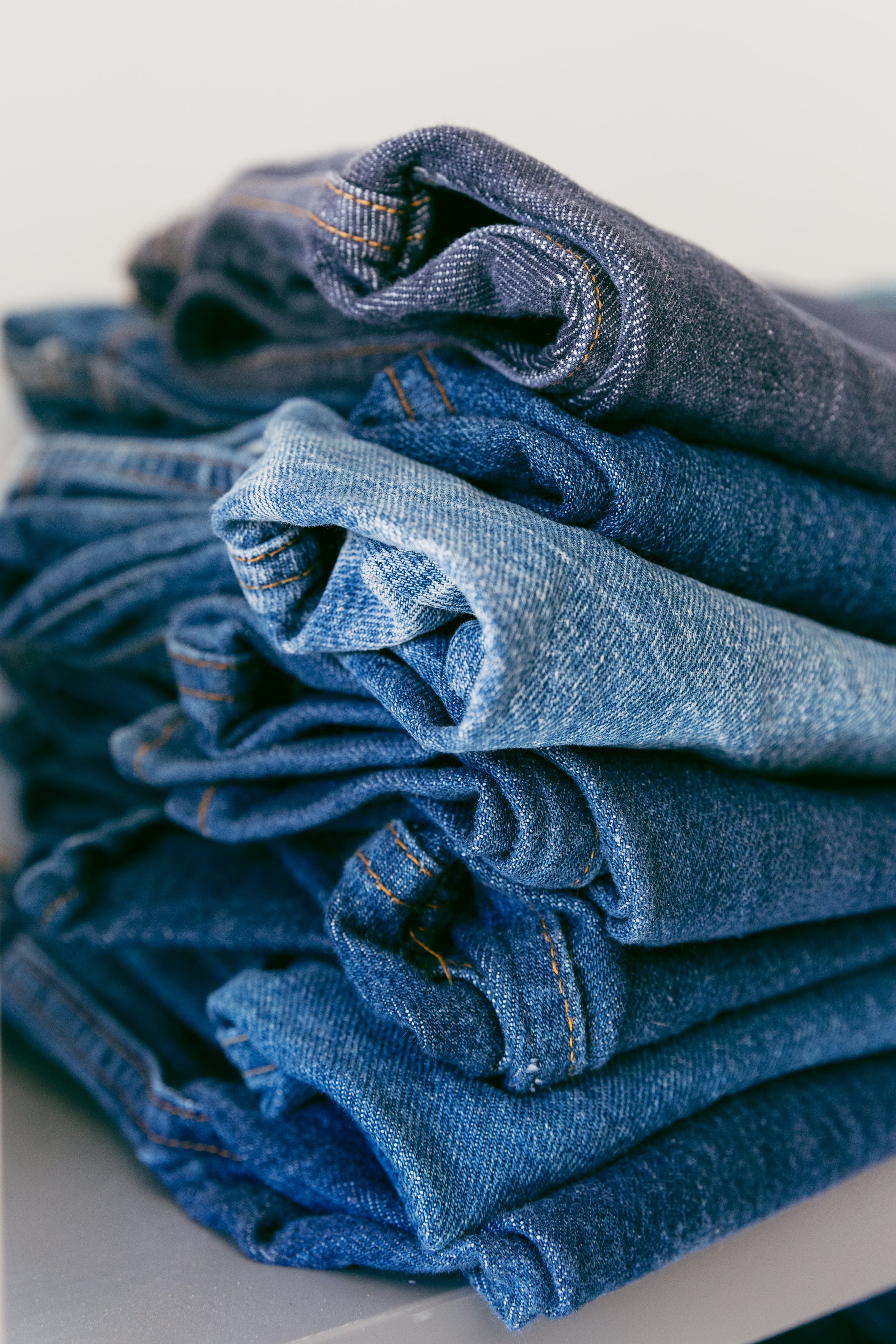 A pile of denim jeans in different shades of blue