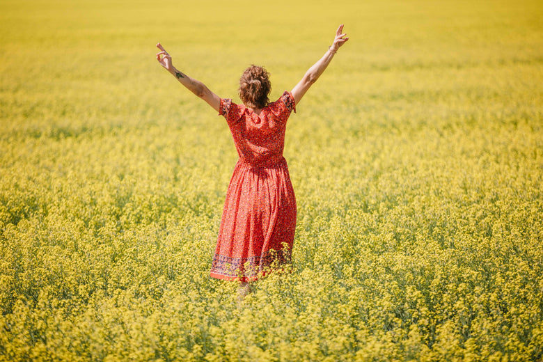 Woman in red dress stands in field of yellow